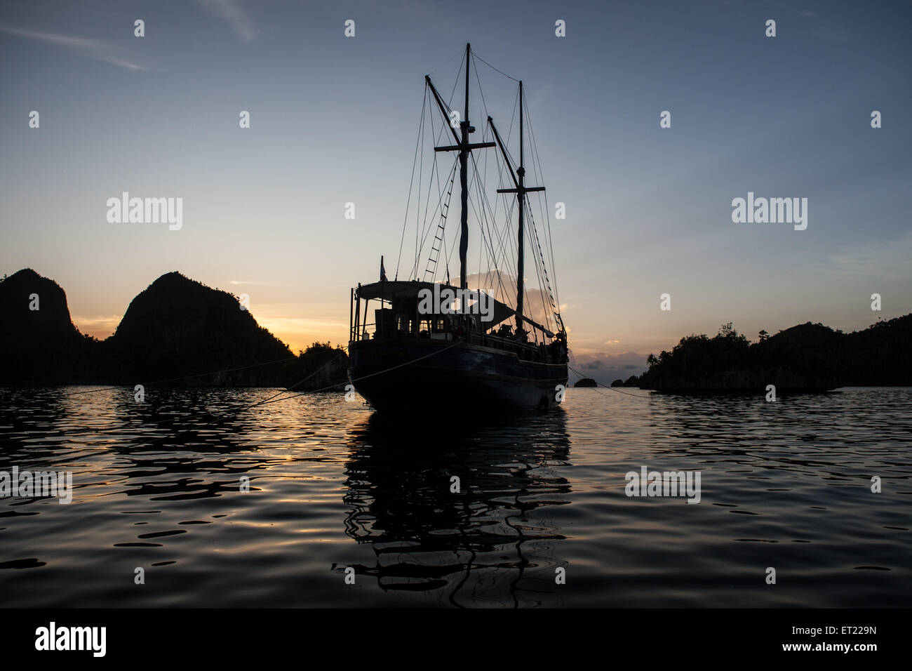 Eine indonesische Pinisi-Schoner liegt vor Anker in der Nähe eine Reihe von abgelegenen Kalksteininseln in Raja Ampat, Indonesien. Stockfoto