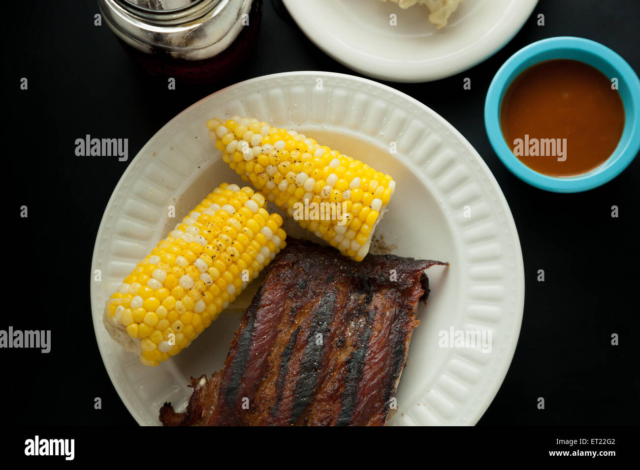 Schweinerippchen auf einem Teller mit Corn Cob, Kartoffelsalat, Eistee und Barbeque-sauce Stockfoto