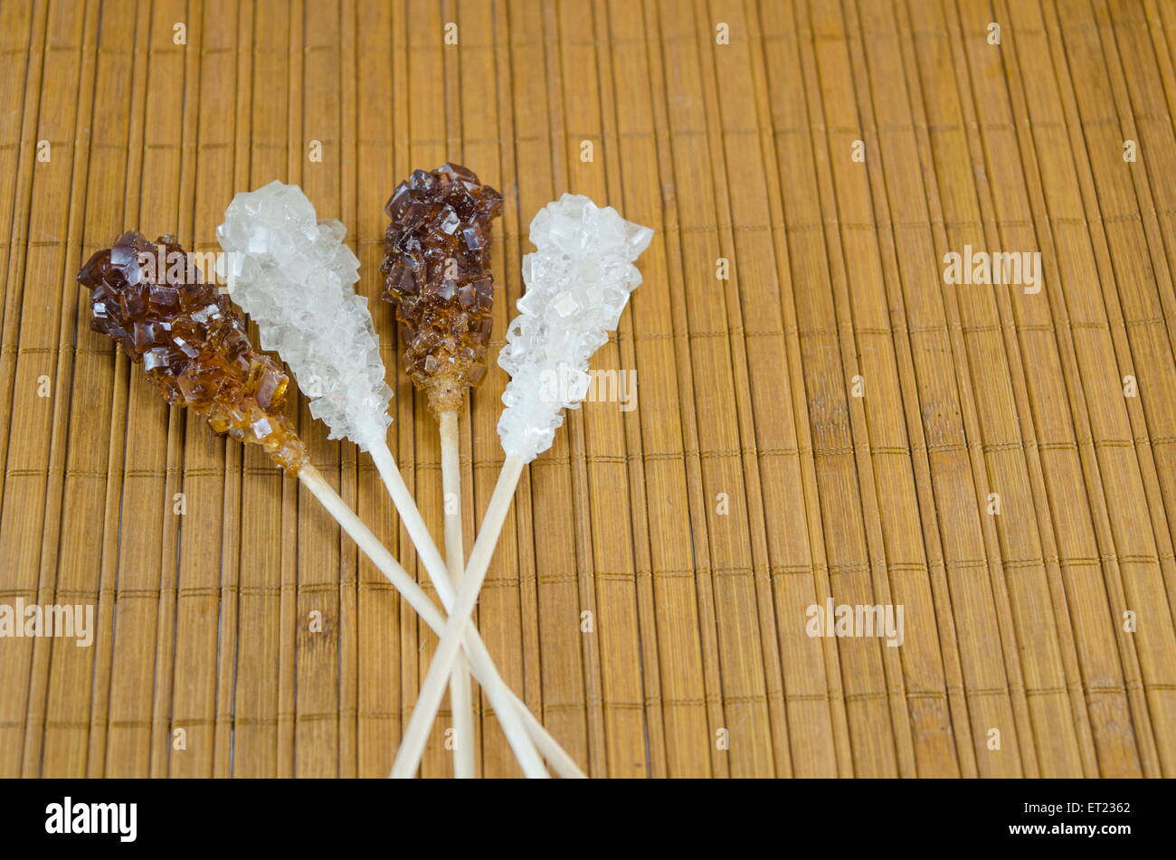 Zwei Zuckersticks mit weißer und brauner Zucker gegen ein Holztisch Stockfoto