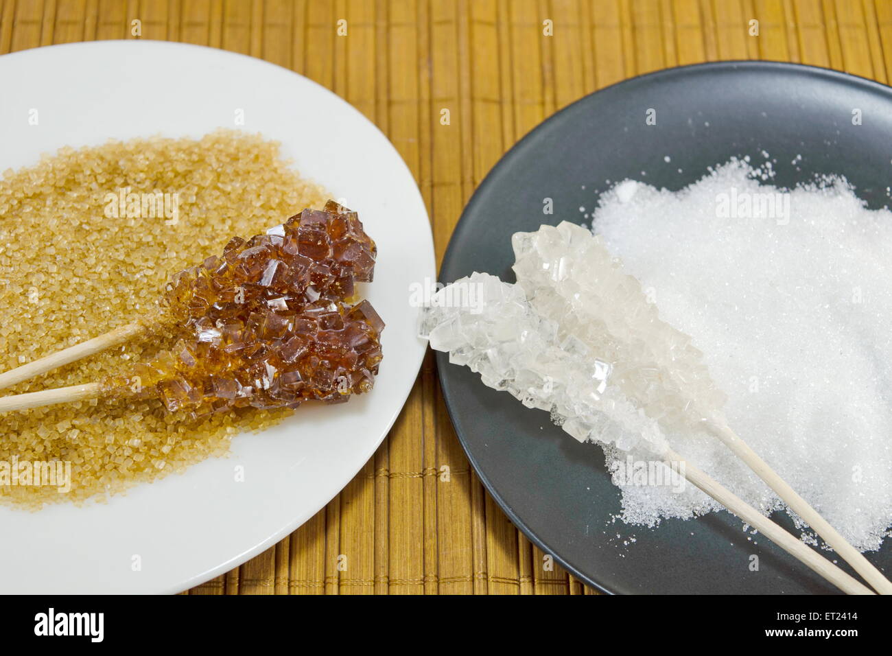 Zwei Zuckersticks mit weißer und brauner Zucker gegen ein Holztisch Stockfoto