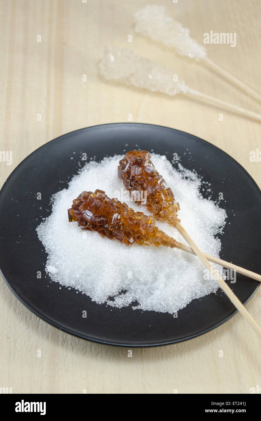 Zwei Zuckersticks mit weißen und braunen Zucker in einer schwarzen Platte Stockfoto