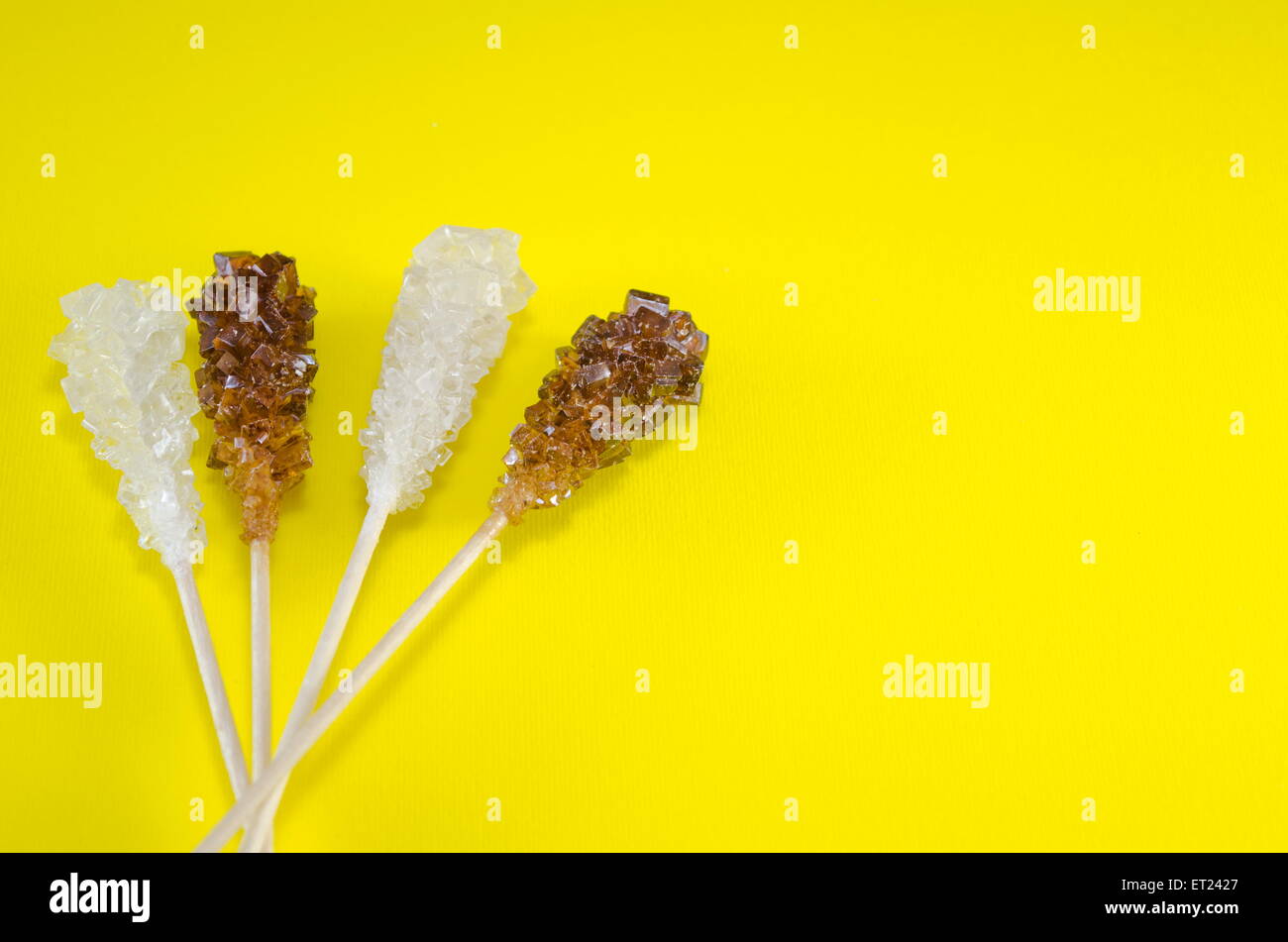 Zwei Zuckersticks mit weißen und braunen Zucker mit gelbem Hintergrund Stockfoto
