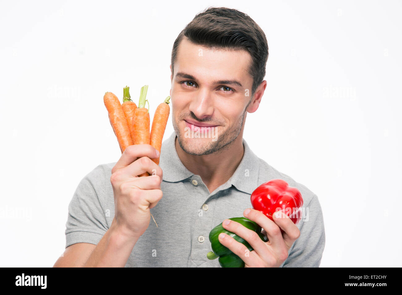 Lächelnde junge Mann hält Gemüse isoliert auf einem weißen Hintergrund. Blick in die Kamera Stockfoto