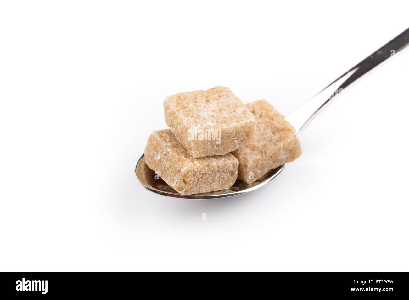 Würfel aus braunem Zucker auf einem Metalllöffel Stockfoto