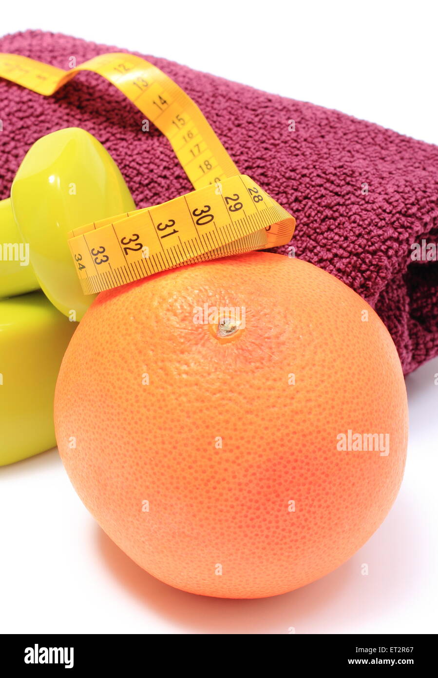 Grüne Hanteln und lila Handtuch für den Einsatz in Fitness, frische Grapefruit und Maßband, Konzept für gesunde Ernährung Stockfoto