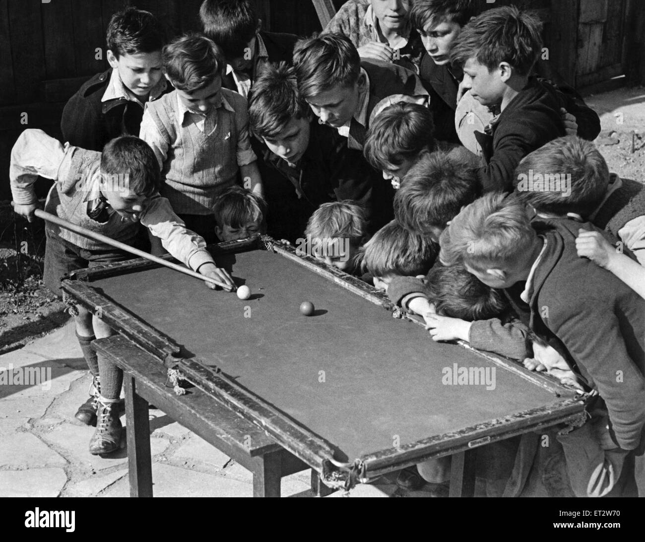 Sechzehn zerzausten Kopf bücken einen klapprigen Billard-Tisch an der Camel Club, Bethnal Grün, wie 11 jährige Ronnie Munday bereitet sich auf einen Schuss Topf. In einer bombardierten Website Bethnal Green, London, wo die Jungs ihre Zeit, Fußball gebootet verbringen Ronnie schafft einen b Stockfoto
