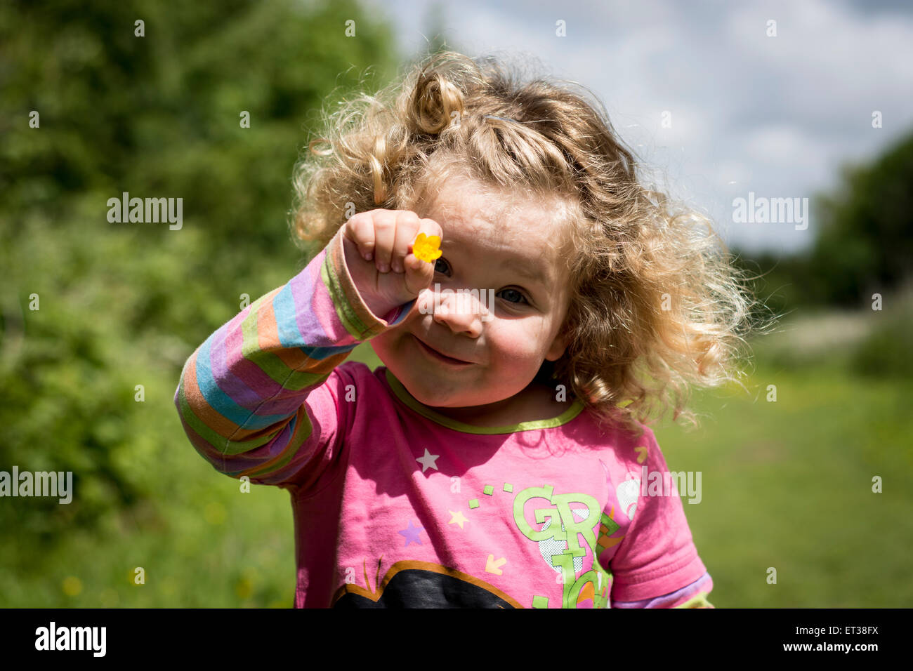 Junge weibliche Mädchen mit Blume auf dem Lande mit Sonnenschein an einem Sommertag. Stockfoto