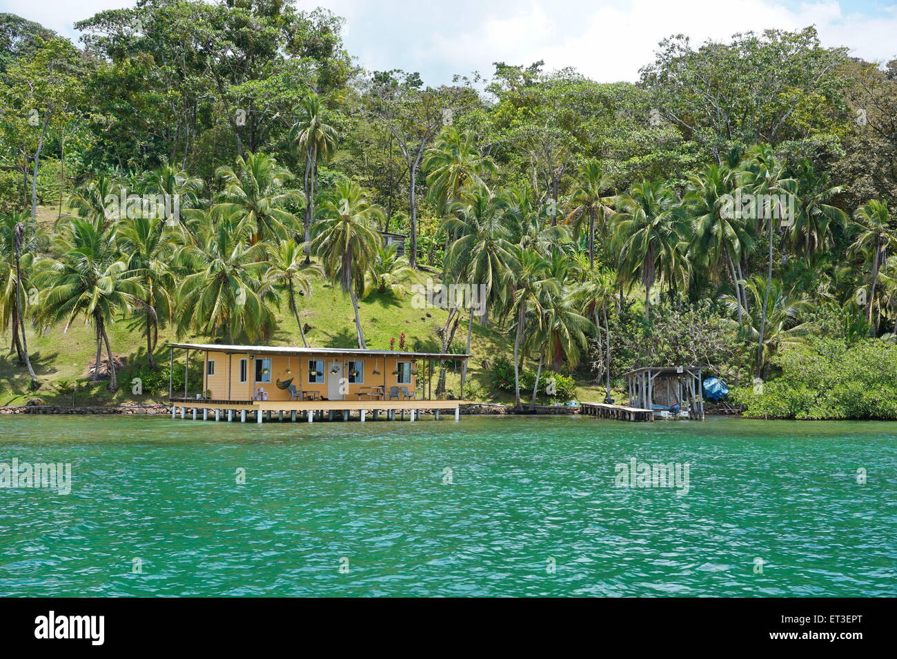 Üppige Küstenlandschaft mit Kokosnuss-Palmen und einem Haus über Wasser, karibische Küste von Panama, Mittelamerika Stockfoto