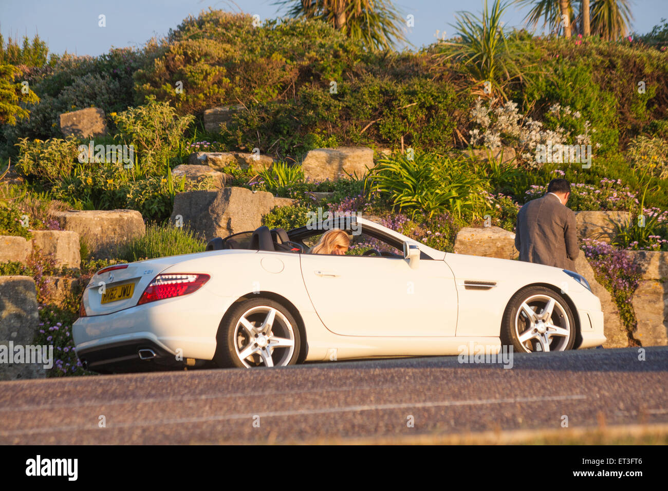 Mercedes-Benz Cabrio Auto unterwegs auf Sandbänken mit Frau saß im Fahrersitz und Mann auf Motorhaube, Poole, Dorset, Großbritannien Stockfoto