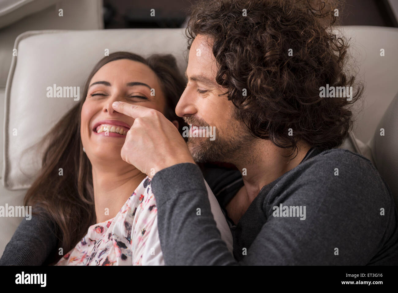 Mitte erwachsenes paar liegt auf Sofa und lächelnd, München, Bayern, Deutschland Stockfoto