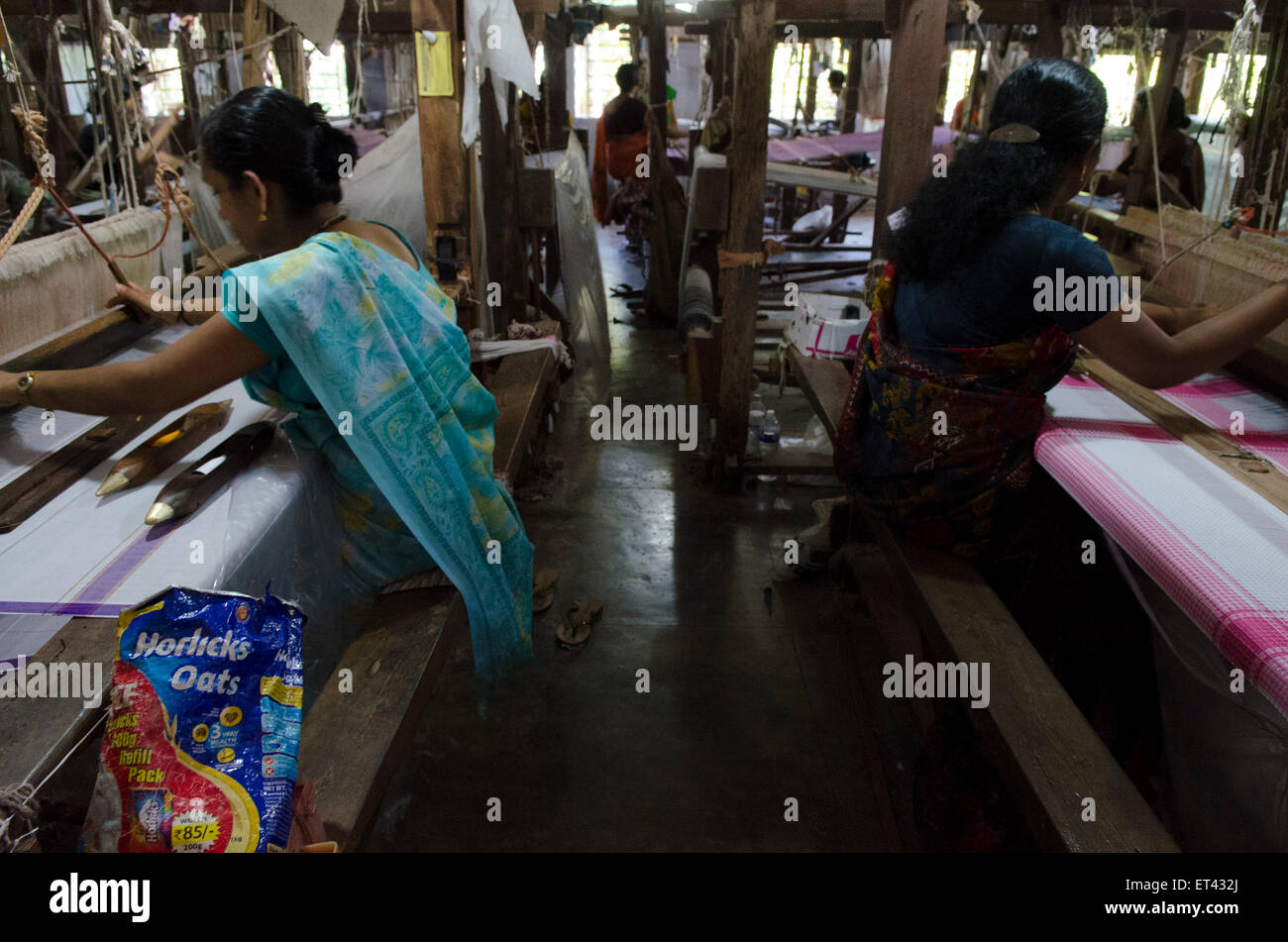 Frauen arbeiten in Reihen an einem Handwebstuhl Fabrik Stockfoto