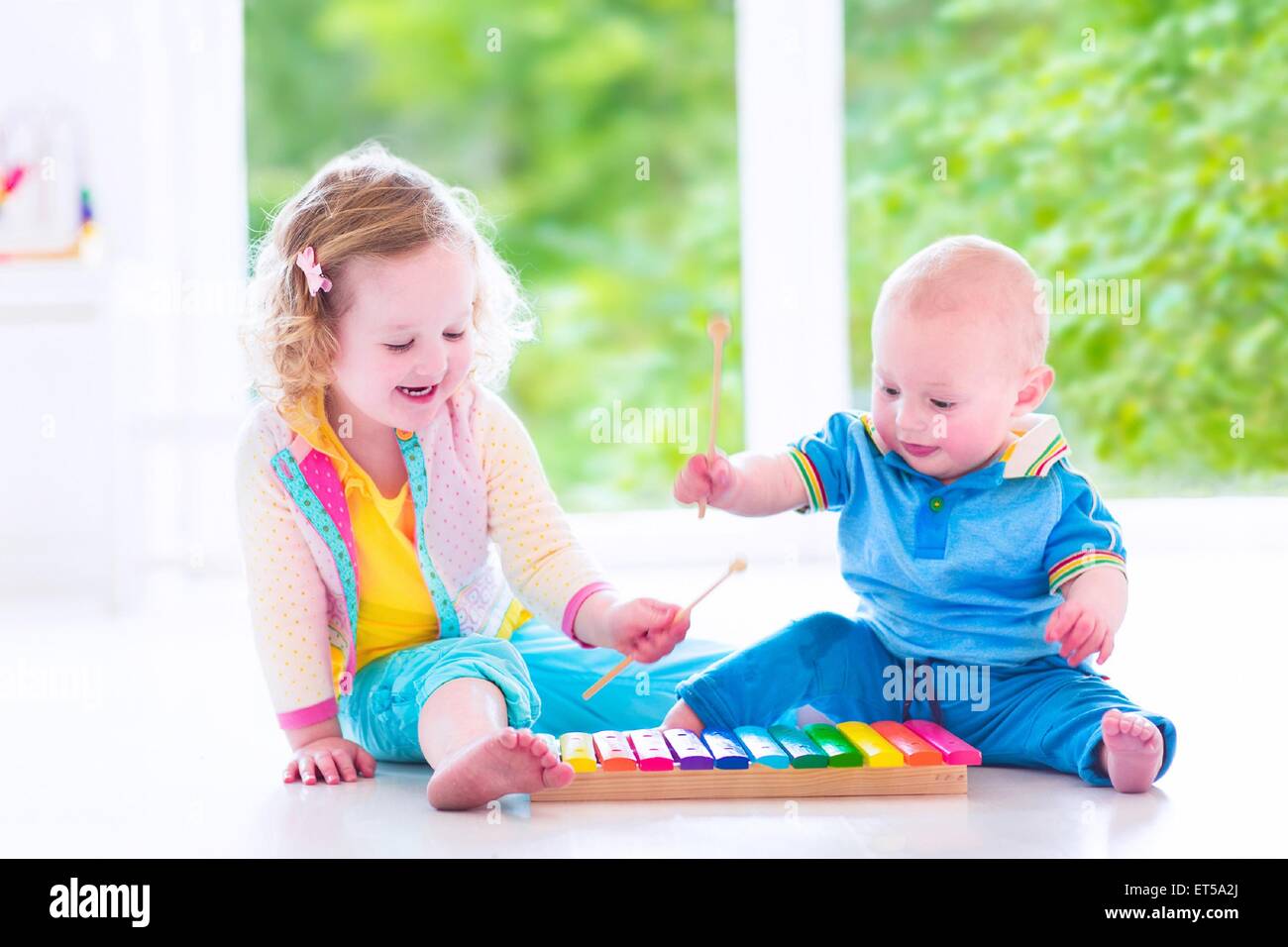 Zwei kleine Kinder - niedliche lockige Kleinkind Mädchen und eine lustige Baby Boy, Bruder und Schwester Musizieren mit bunten Xylophon Stockfoto