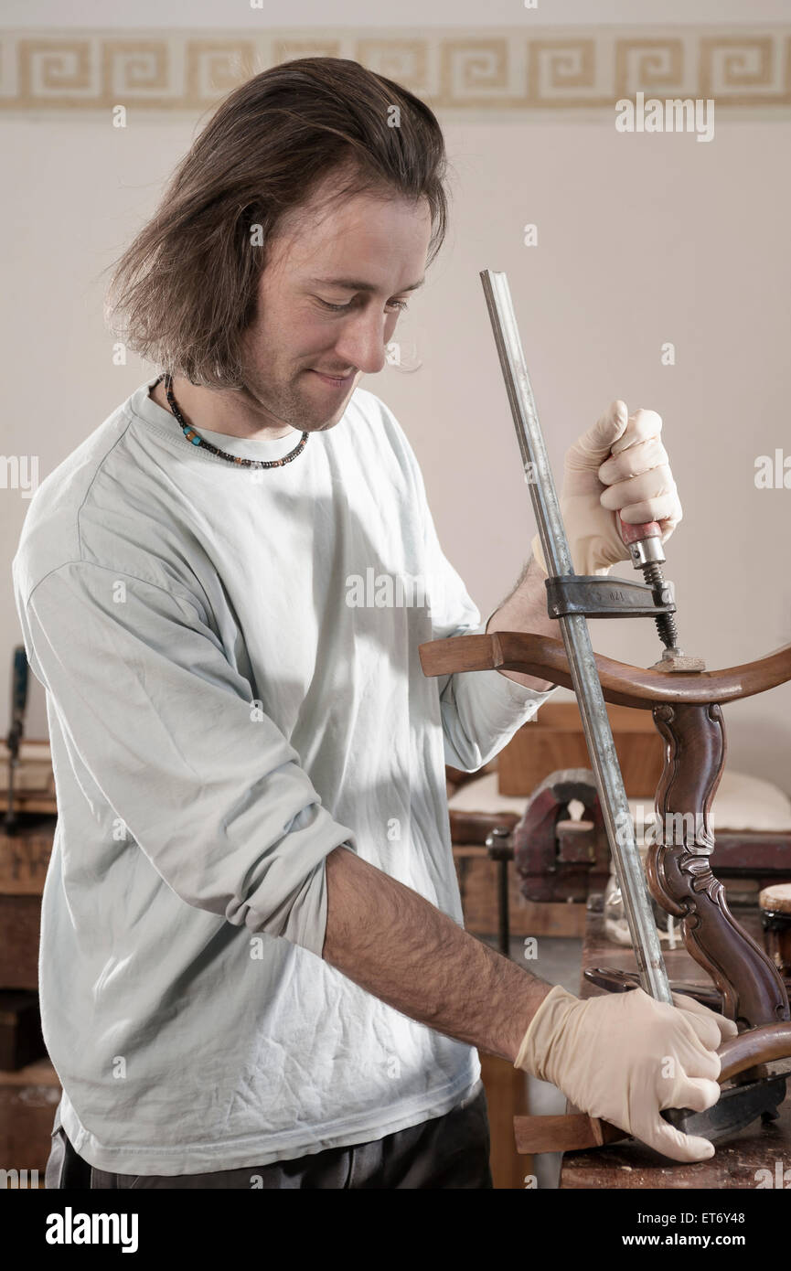 Tischler, Befestigung einen Schraubstock, ein antiker Holzstuhl im Workshop, Bayern, Deutschland Stockfoto