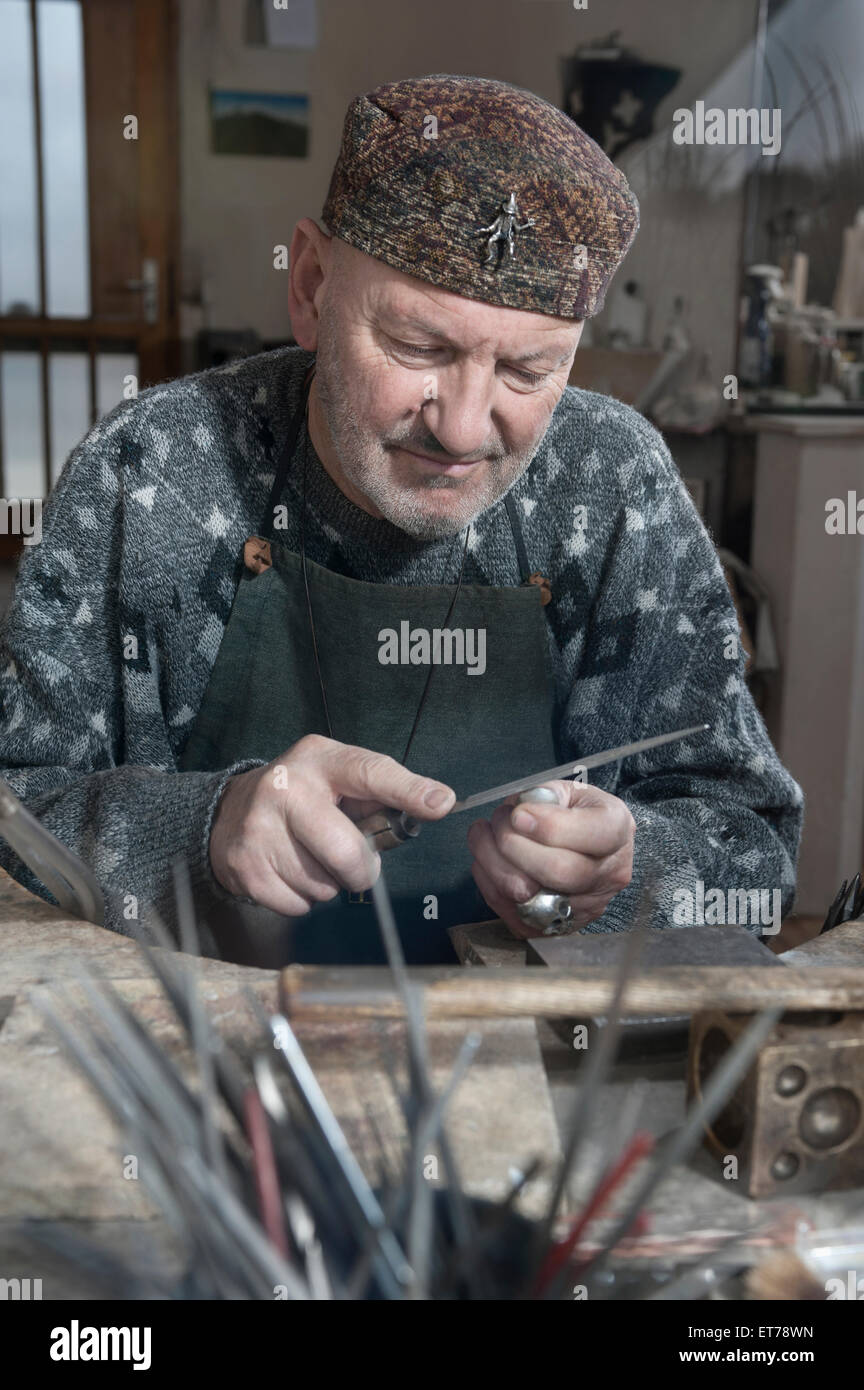 Ältere männliche Goldschmied Gestaltung Kristall mit Raspel in Werkstatt, Bayern, Deutschland Stockfoto