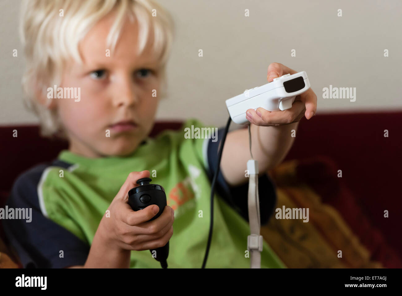 7 Jahre alten Sohn zu Hause spielen Nintendo Wii Computerspiel mit Nintendo-game-Controller in der Hand. Stockfoto