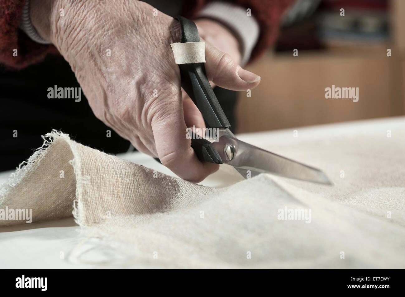 Ältere weibliche Mode-Designer Schneiden Stoff mit einer Schere in Werkstatt Bayern Stockfoto