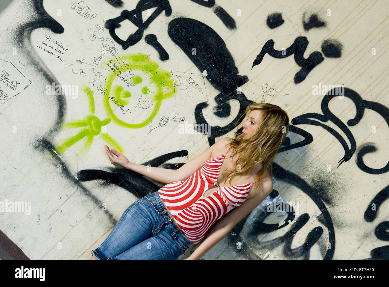 Junge Frau Haelt Haendchen Mit Einem Gesprayten Maennchen Auf Graffitiwand | junge Frau, die Hand in Hand mit einem bemalten Graffiti-m Stockfoto