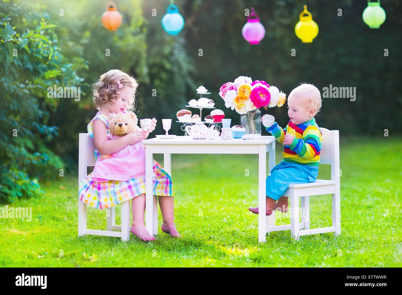 Zwei glückliche Kinder, niedliche lockige Kleinkind Mädchen und ein kleines Baby Boy, Bruder und Schwester, genießen eine Tee-Party mit ihren Spielsachen Stockfoto