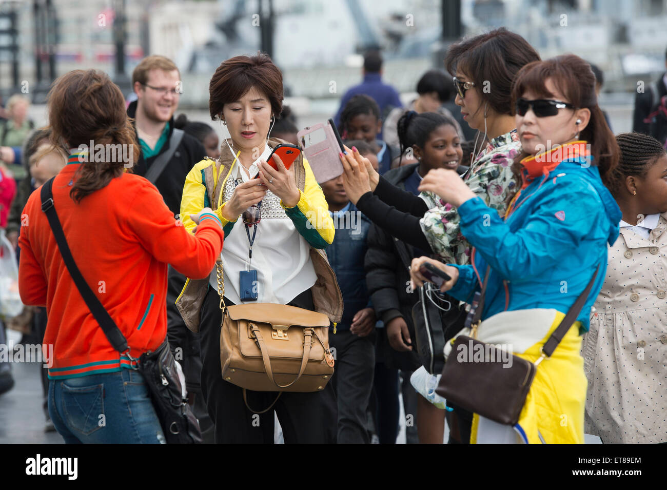Japanische Touristen an der Themse in London mit ihren smartphones Stockfoto