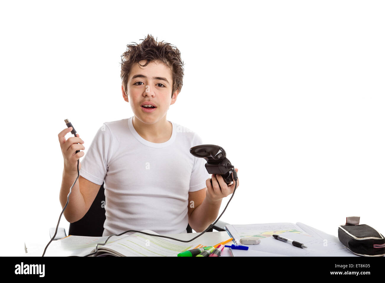 Kaukasische junge in kurzarm T-shirt versuchen, den USB-Stecker von einem game-Controller mit Hausaufgaben Zeug auf Schreibtisch verbinden Stockfoto