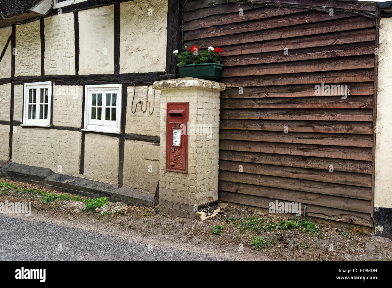 Roten Briefkasten mit Geranien wachsen an der Spitze. Stockfoto
