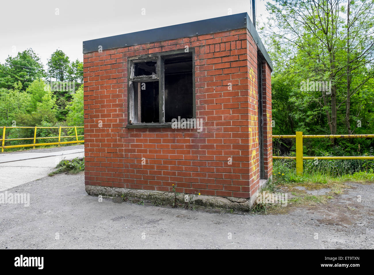 Zerbrochenes Fenster in einem verlassenen Sicherheitsbüro außerhalb einer verlassenen und stillgelegten Fabrik Stockfoto
