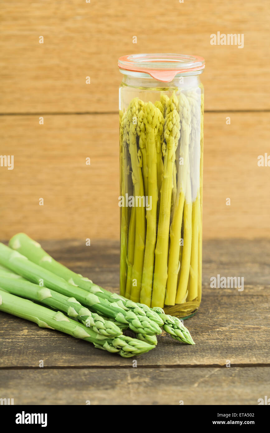 Grüner Spargel im Glas und frischer grüner Spargel auf Holztisch erhalten Stockfoto