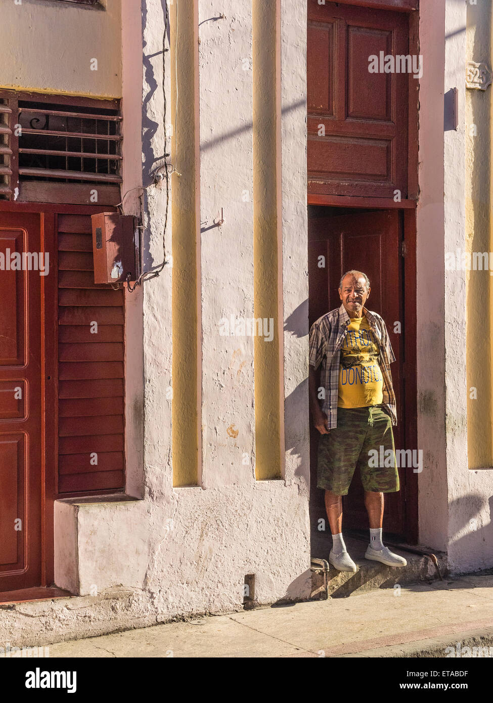 Hispanic Mann stand in den frühen Morgenstunden Licht in Tür öffnen in der Innenstadt von Santiago De Cuba. Stockfoto