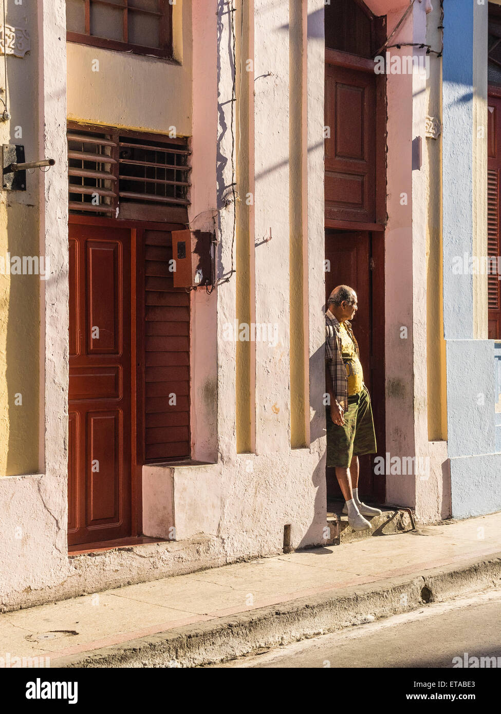 Hispanic Mann stand in den frühen Morgenstunden Licht in Tür öffnen in der Innenstadt von Santiago De Cuba. Stockfoto