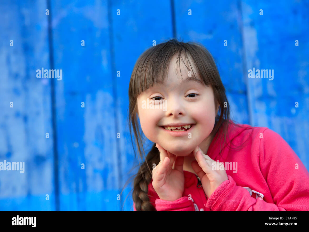 Junges Mädchen lächelnd auf Hintergrund der blauen Wand Stockfoto