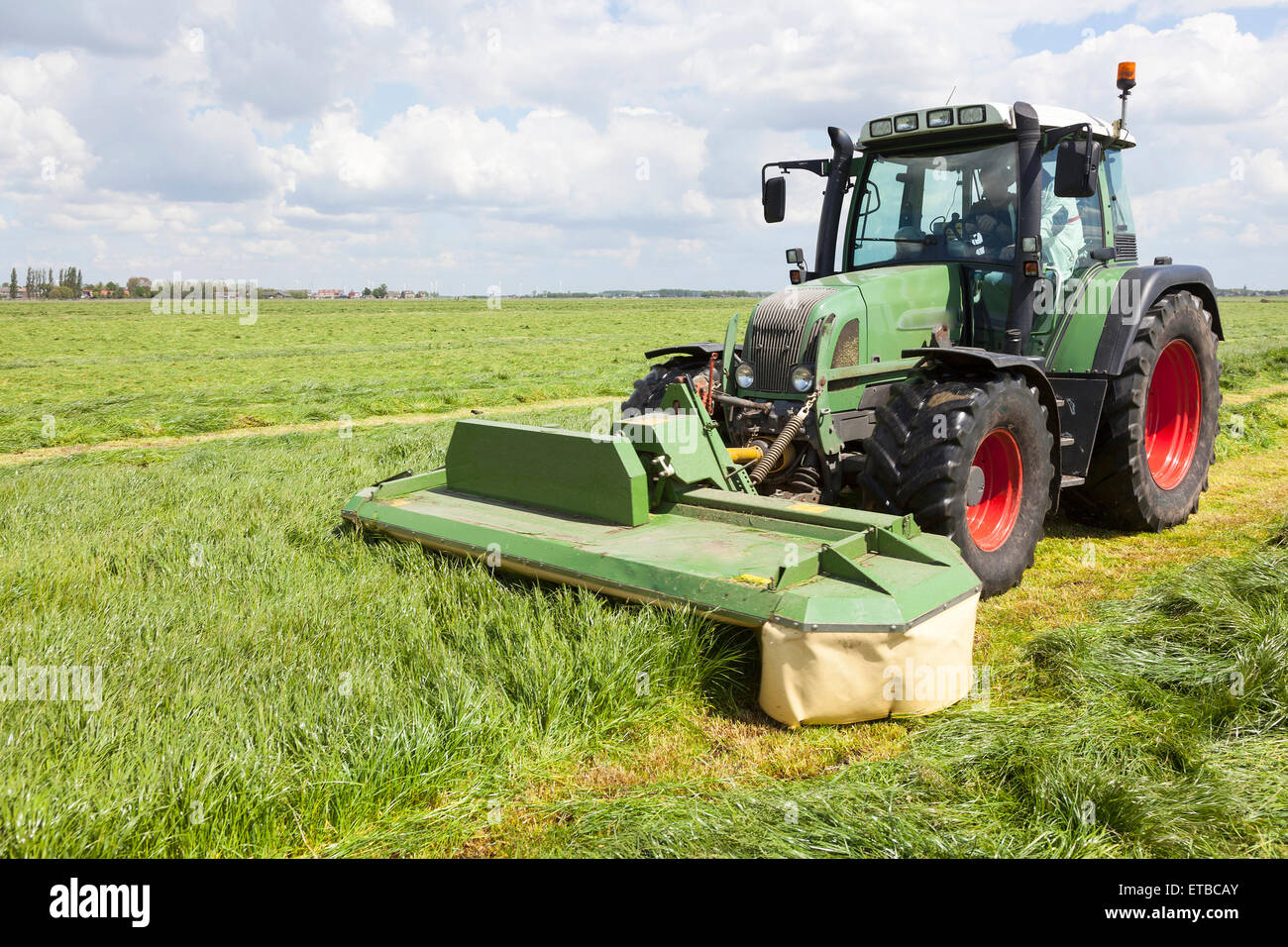 Traktor und Mähwerk auf grüner Wiese in den Niederlanden an sonnigen Tag  Stockfotografie - Alamy