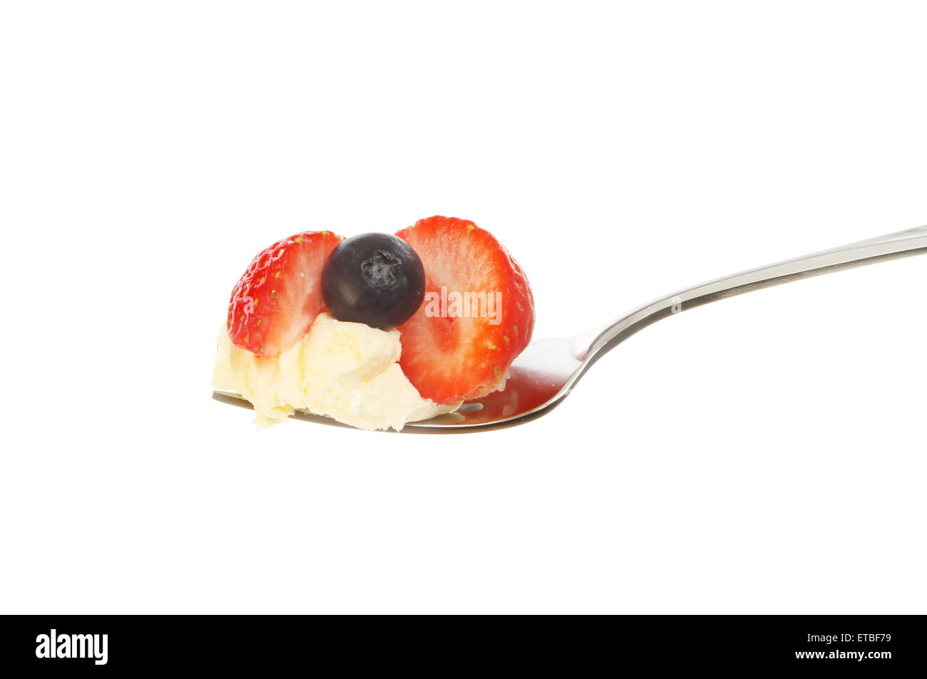 Erdbeere und Heidelbeere mit Clotted Cream auf einer Gabel isoliert gegen weiß Stockfoto