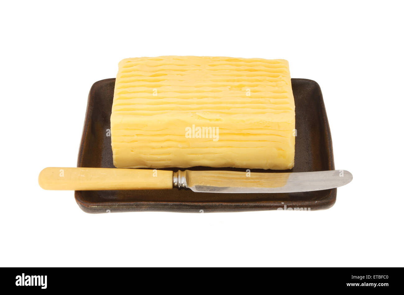 Block von Butter und Buttermesser auf einem Teller isoliert gegen weiß Stockfoto