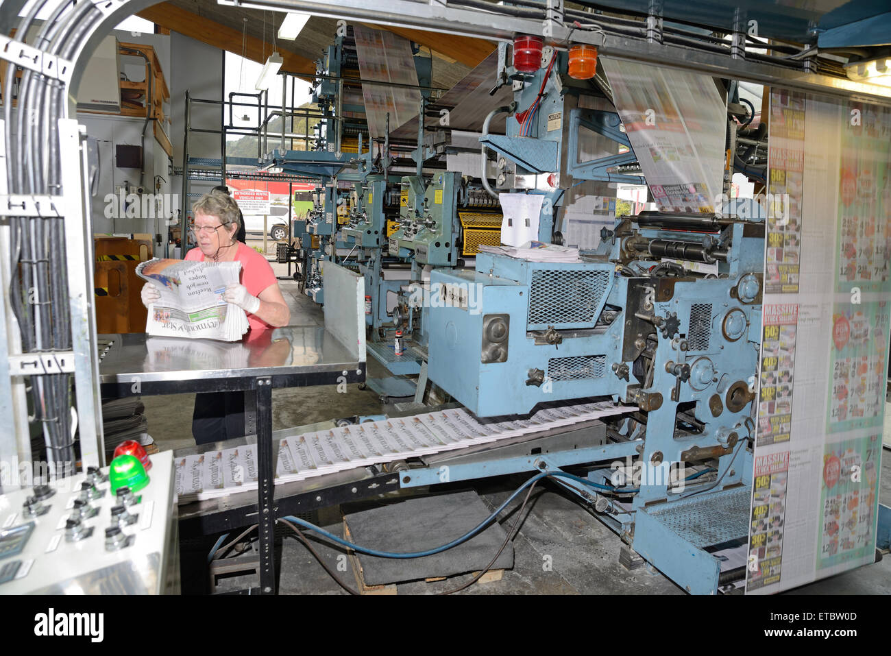 GREYMOUTH, Neuseeland, 22. Mai 2015: Eine unbekannte Frau bündelt sich Zeitungen wie sie gedruckt werden Stockfoto