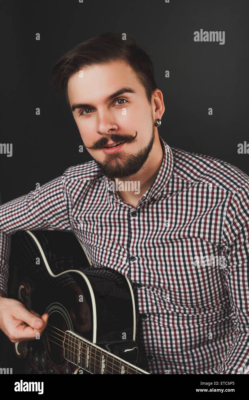 gut aussehend Mann mit Bart hält Akustikgitarre Stockfoto