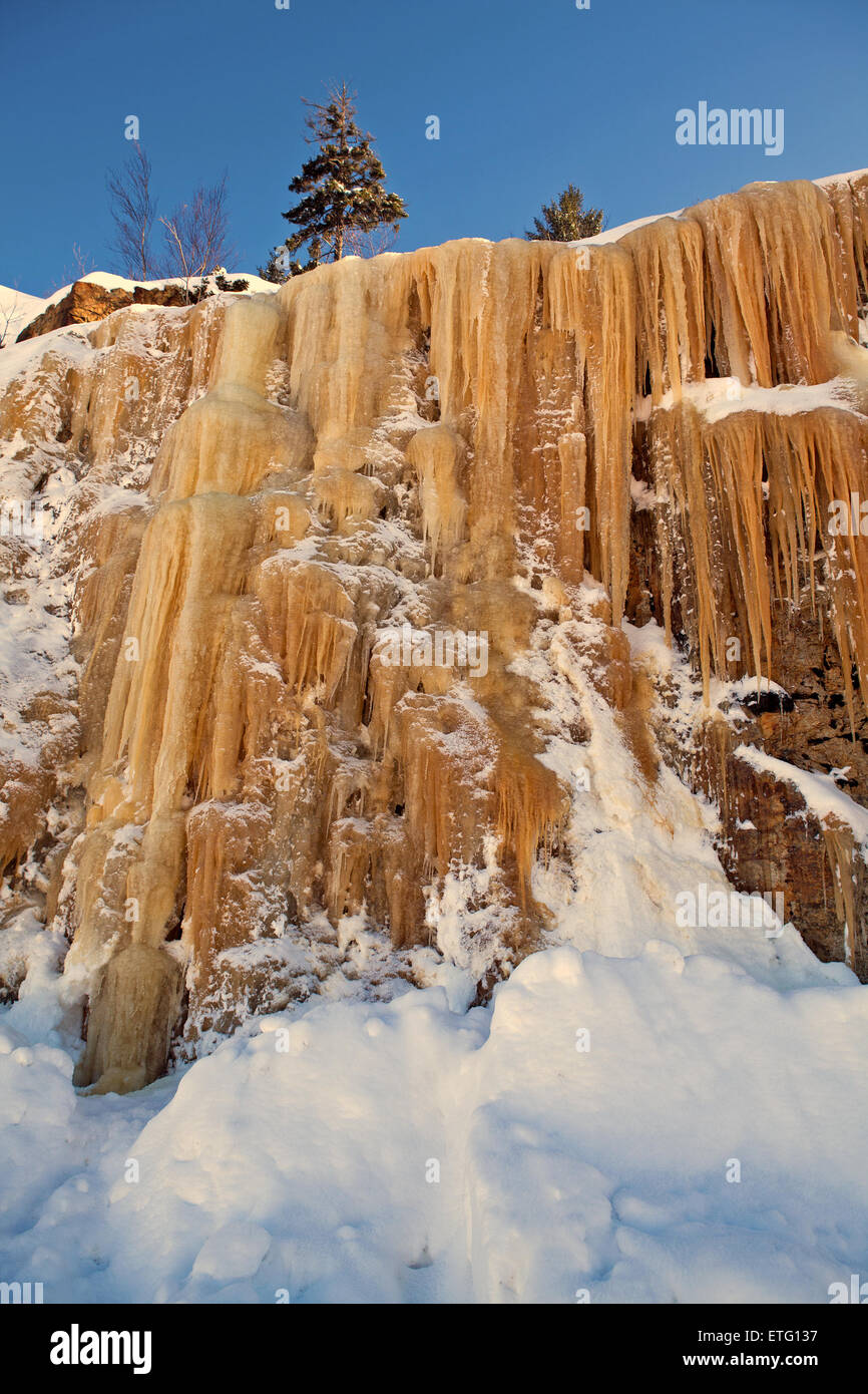 Orange farbigen Eiszapfen abstürzende eine Felswand, verursacht durch Eisenminerale in Boden und Wasser. Stockfoto