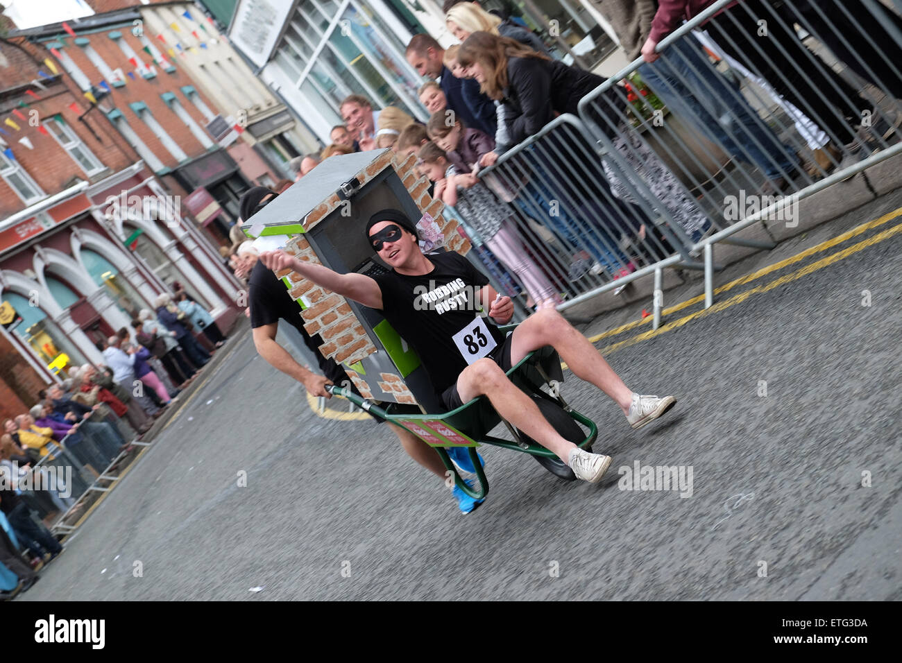 Kington, Herefordshire, England. 13. Juni 2015. Kington Festival Schubkarren Rennen Konkurrenten in der diesjährigen raste 39. Schubkarren-Rennen in der Stadt zu trinken an jedem Pub auf dem Weg zu stoppen. Hier zwei Konkurrenten als Geldautomat Räuber Rennen durch die Innenstadt werfen Sie Falschgeld nach einigen Pints unterwegs verkleidet. Stockfoto