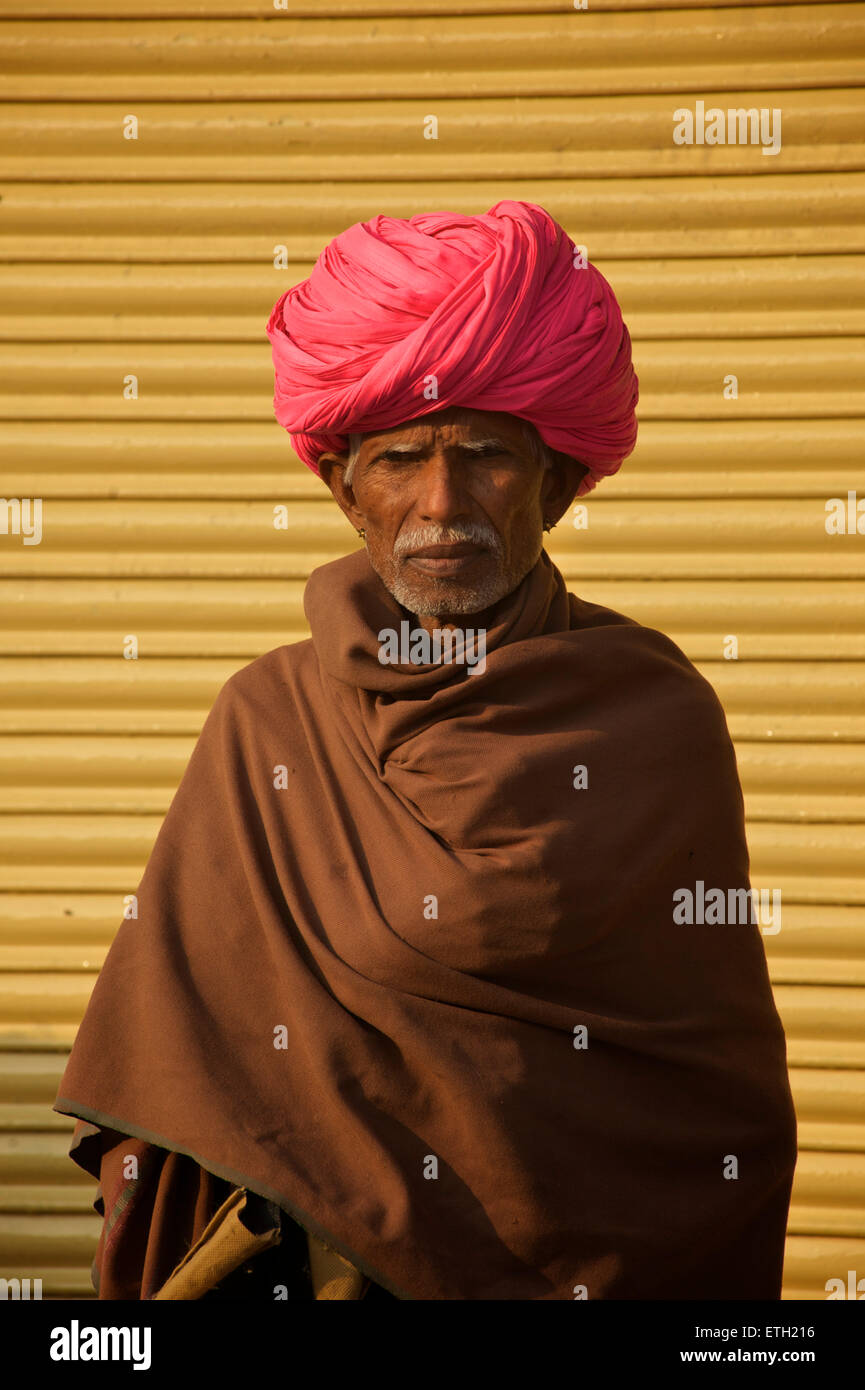 Indischer Mann in rosa Turban gegen gelben Fensterläden, Jodhpur, Rajasthan, Indien Stockfoto