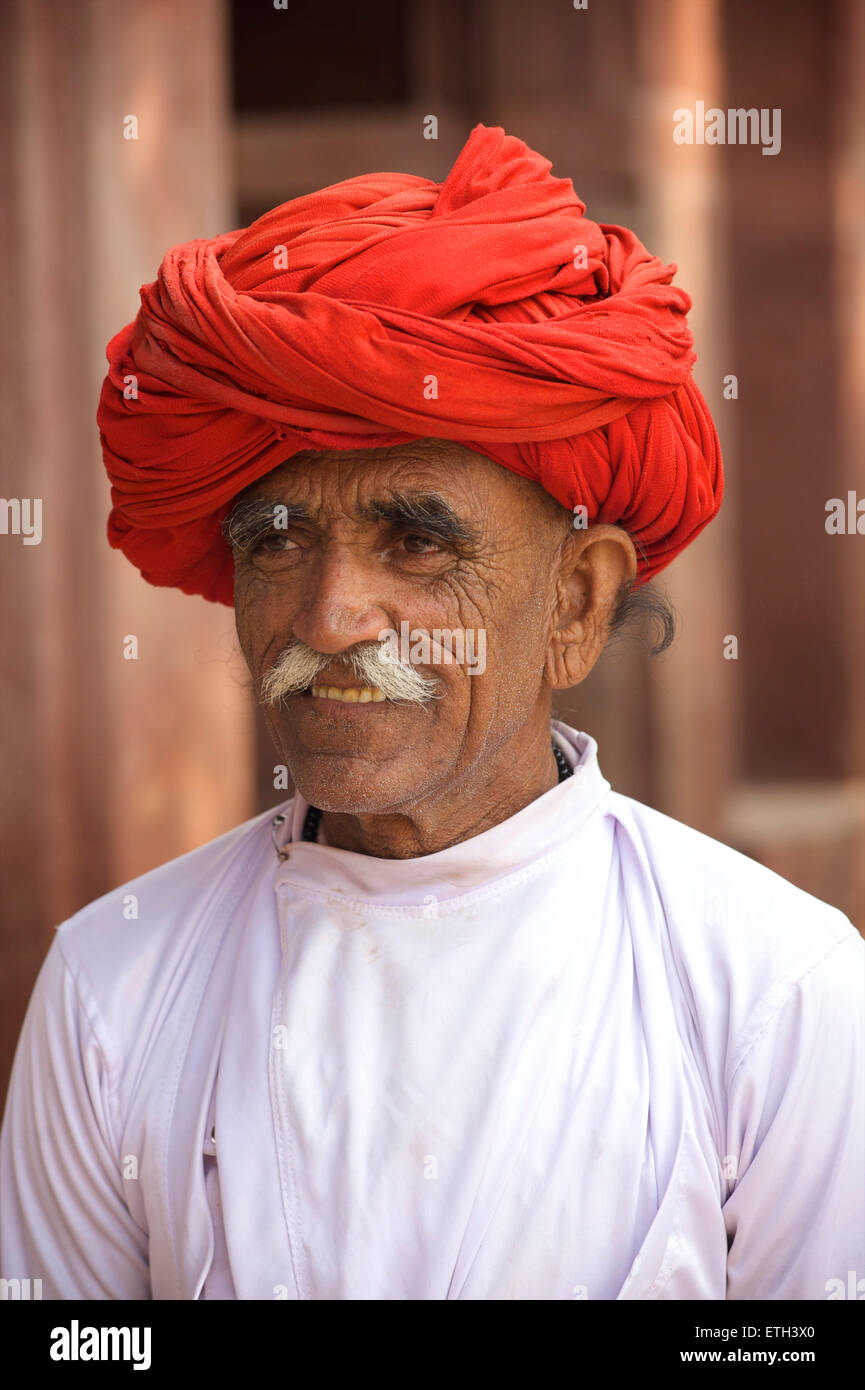 Rajasthani Mann in weiß mit markanten roten Turban. Ländliches Dorf in der Nähe von Jodhpur, Rajasthan, Indien Stockfoto