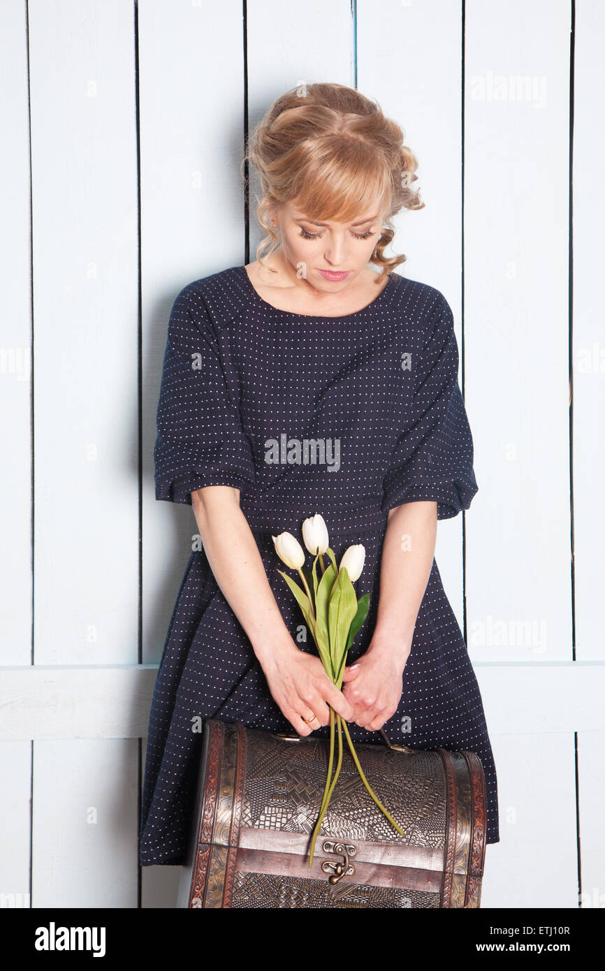 Hübsche Frau mit Blumen in der Hand und einem Koffer Stockfoto