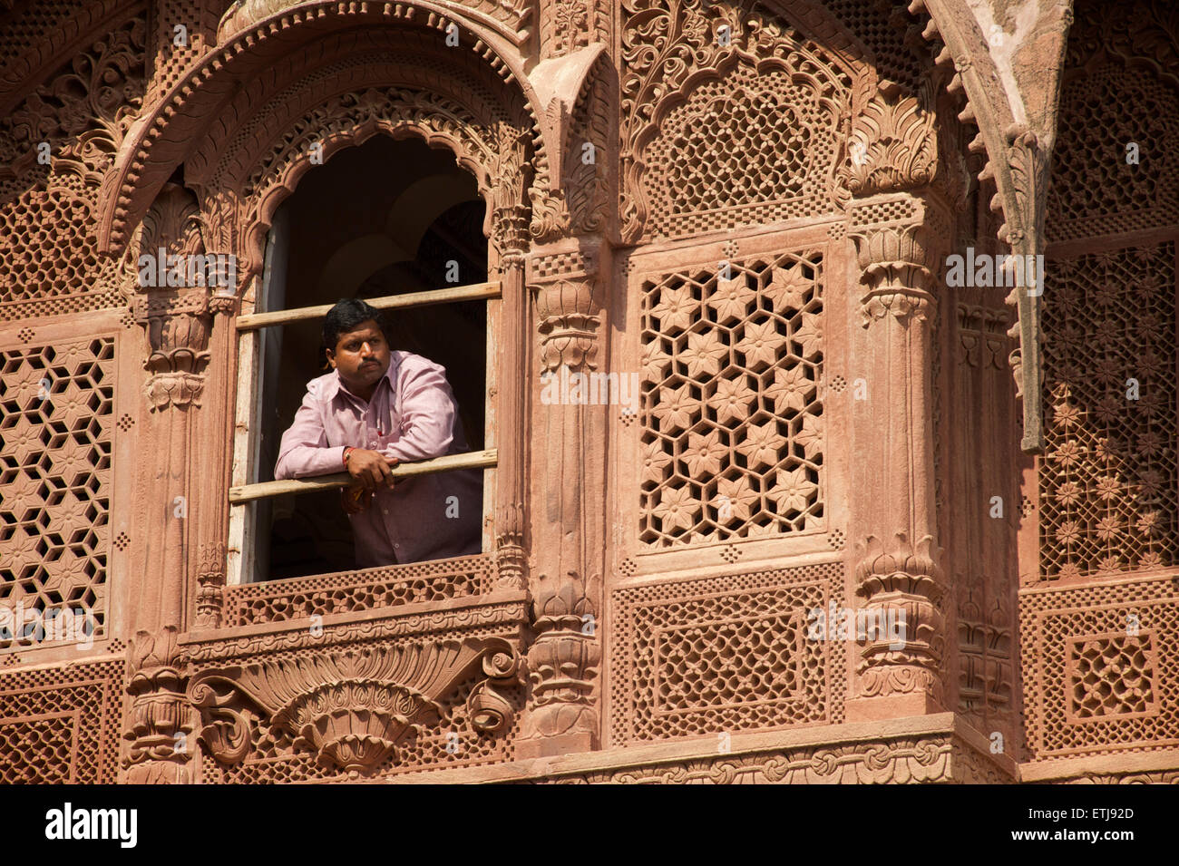 Indischer Mann mit Blick vom Fenster in geschnitzten Fassade an Mehrangarh Fort, Jodhpur, Rajasthan, Indien Stockfoto