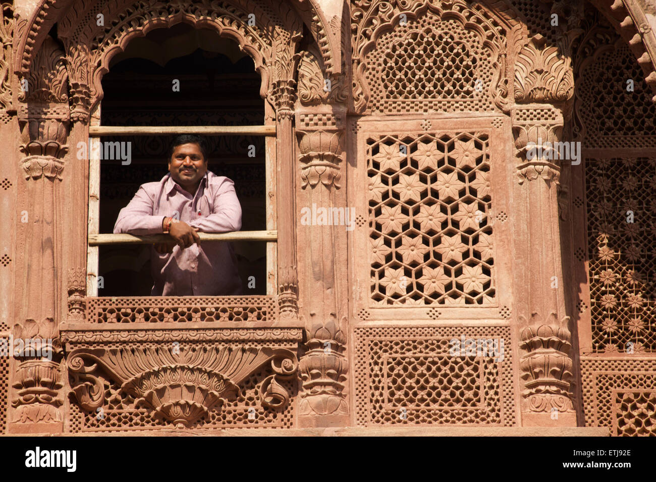 Indischer Mann mit Blick vom Fenster in geschnitzten Fassade an Mehrangarh Fort, Jodhpur, Rajasthan, Indien Stockfoto