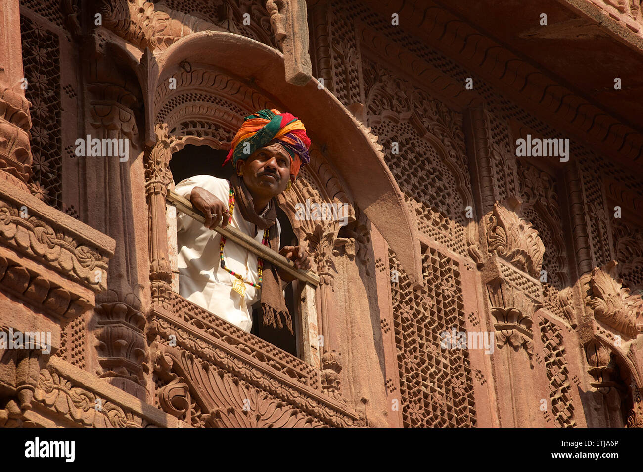 Rajasthani Mann mit Blick vom Fenster in geschnitzten Fassade an Mehrangarh Fort, Jodhpur, Rajasthan, Indien Stockfoto
