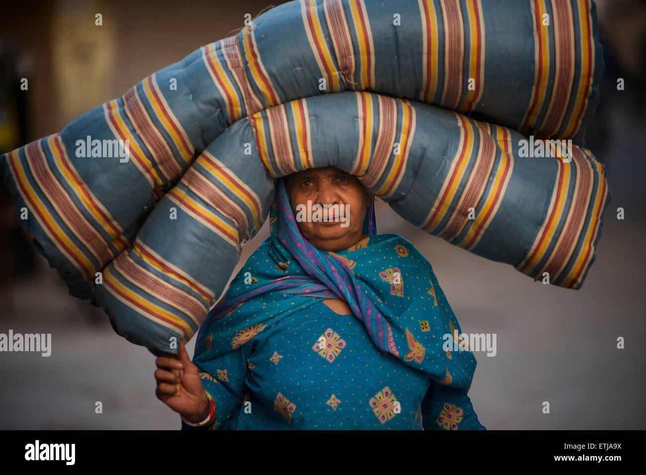 Indische Frau in Sari tragen eine gefaltete Matratze auf dem Kopf, Jodhpur, Rajasthan, Indien Stockfoto
