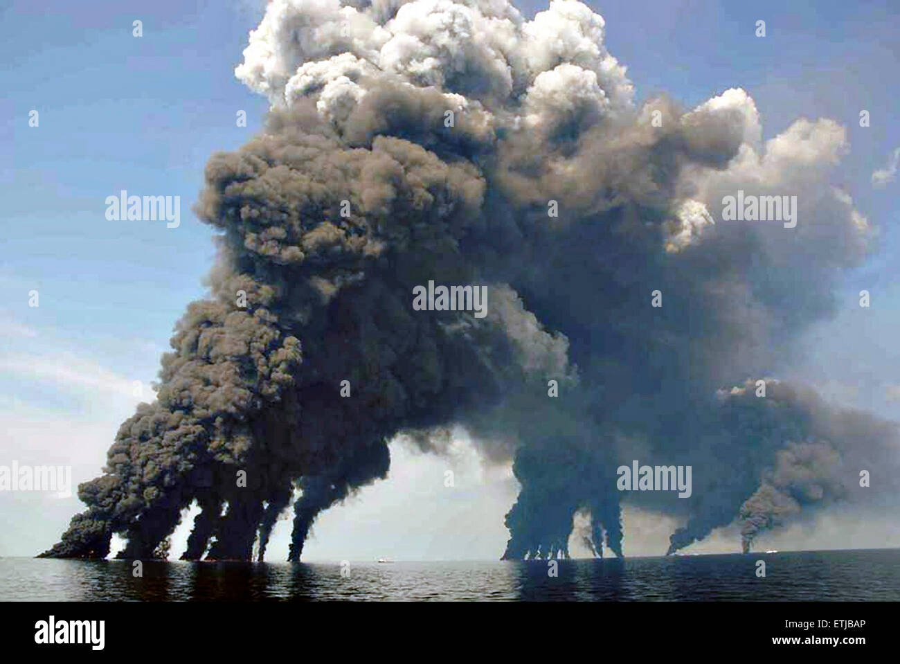 Dunkle Wolken füllen den Himmel wie Krabbenkutter einen Boom verwenden, um Erdöl zu sammeln, während eine kontrollierte Oberfläche brennen nach der BP Deepwater Horizon-Ölkatastrophe als Bemühungen zur Eindämmung und reinigen Sie die Millionen von Gallonen Crew weiter 19. Juni 2010 im Golf von Mexiko. Stockfoto