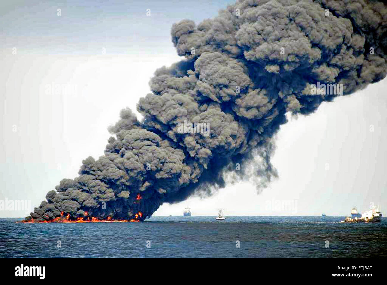 Dunkle Wolken füllen den Himmel wie Krabbenkutter einen Boom verwenden, um Erdöl zu sammeln, während eine kontrollierte Oberfläche brennen nach der BP Deepwater Horizon-Ölkatastrophe als Bemühungen zur Eindämmung und reinigen Sie die Millionen von Gallonen Crew weiter 20. Juni 2010 im Golf von Mexiko. Stockfoto