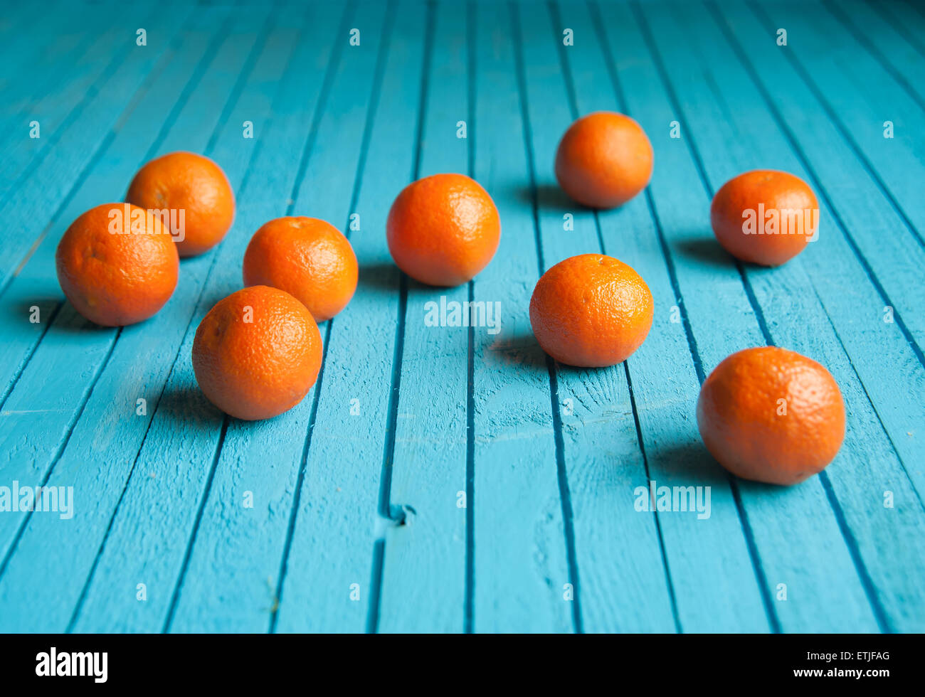 viele Mandarinen liegen auf einem Tisch aus Holz, blau Stockfoto