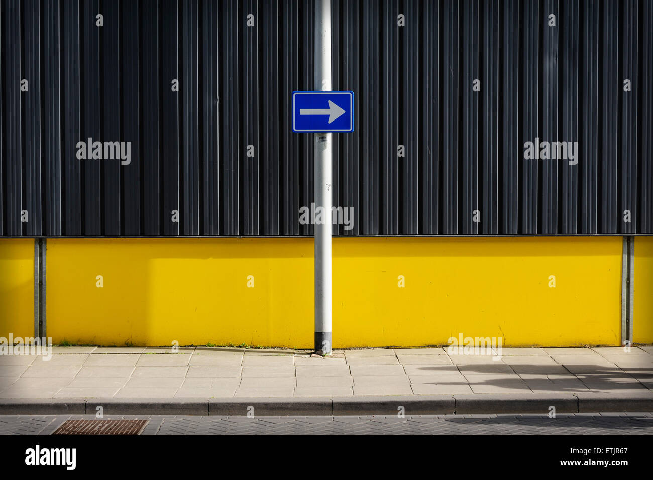 Verkehrsschild, Pfeil rechts gegen gelbe Wand zeigend Stockfoto