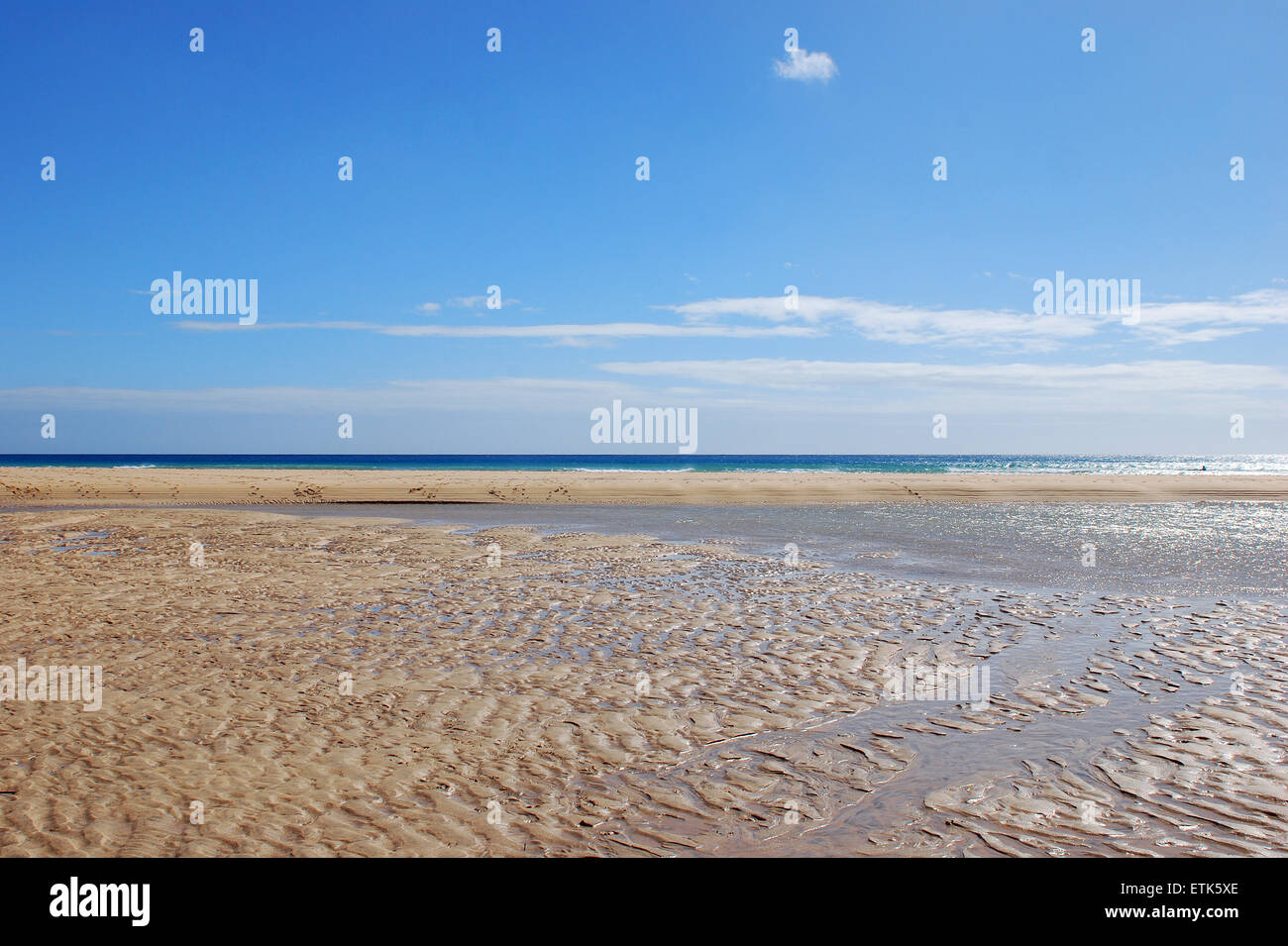 Fuerteventura, Kanarische Inseln. Einem nassen Strand an einem sonnigen Tag mit dem Meer am Horizont, wo das Wasser kleine Pfützen gebildet hat, Stockfoto