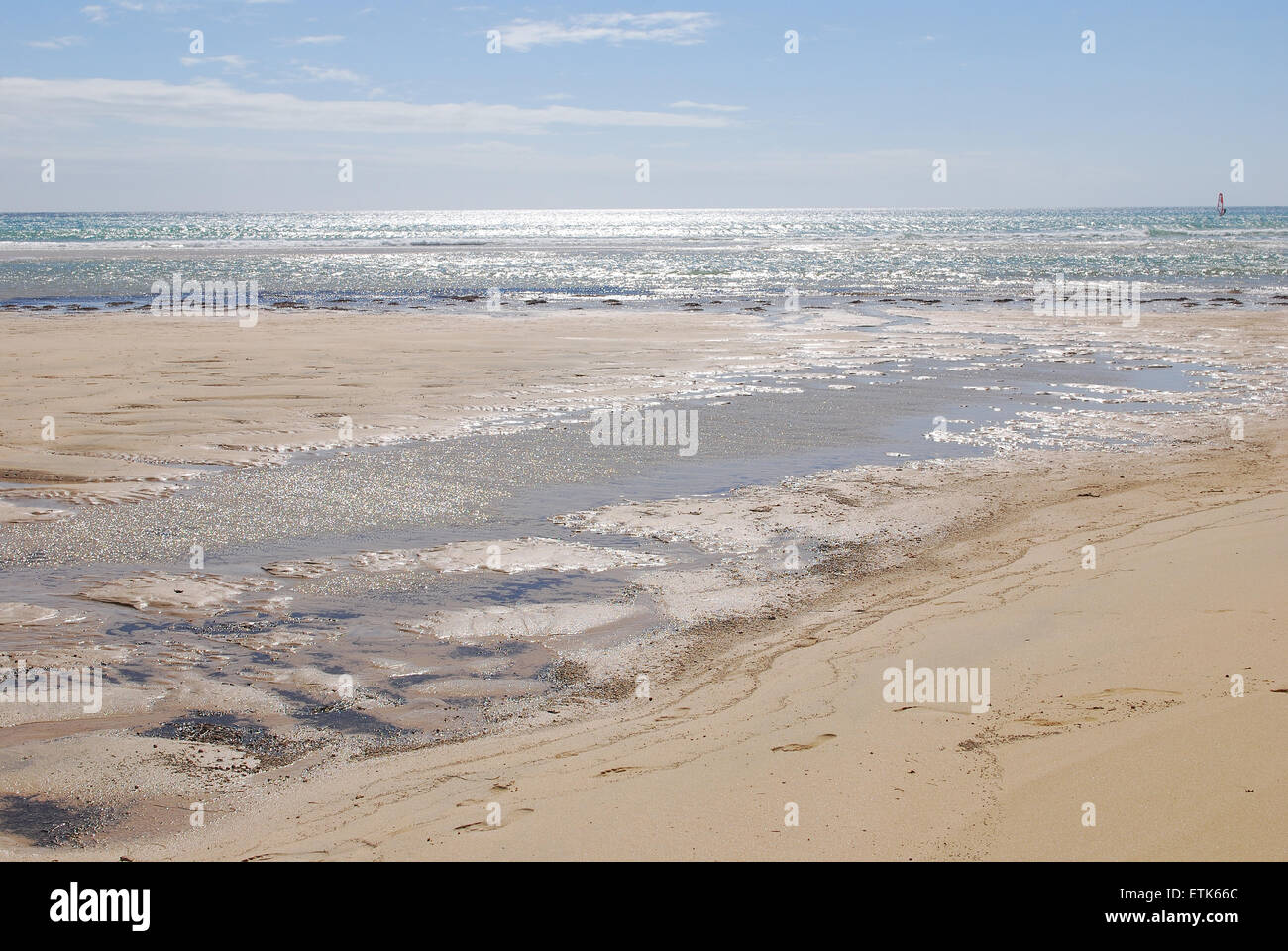 Fuerteventura, Kanarische Inseln. Einem nassen Strand an einem sonnigen Tag mit dem Meer am Horizont, wo das Wasser kleine Pfützen gebildet hat, Stockfoto